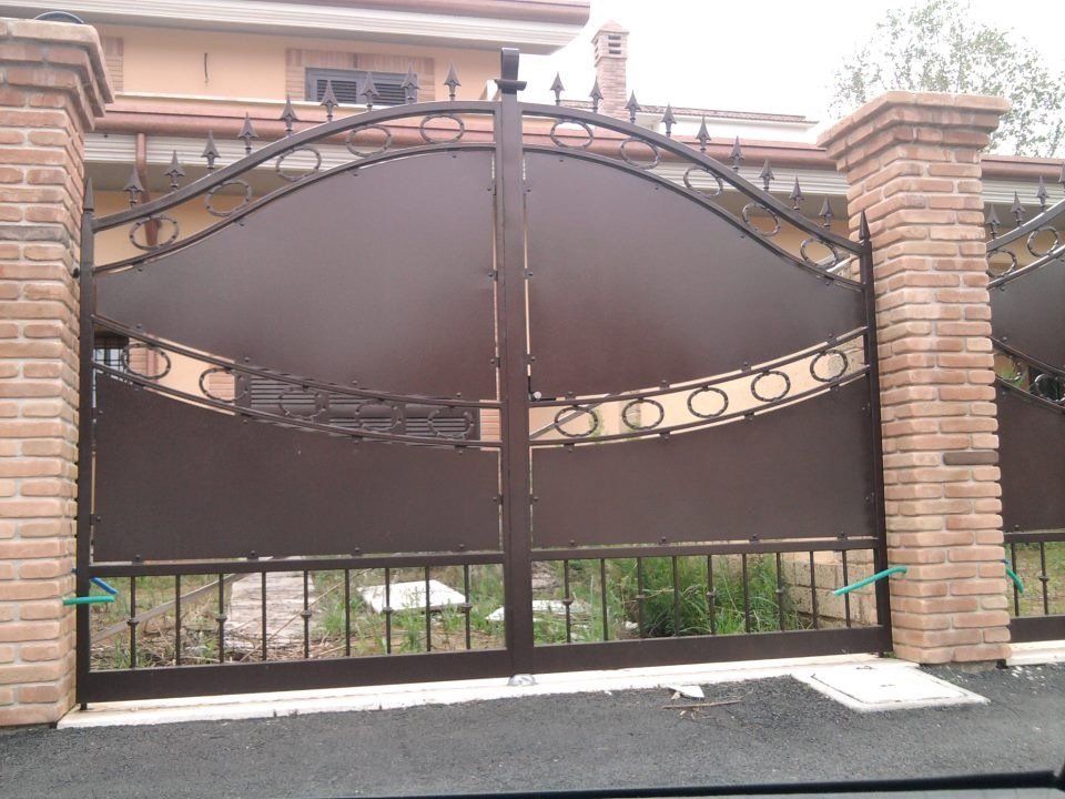 Cancello carrabile ad arco tra pilastri in mattoni