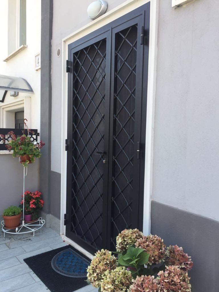 Porta grata a rombi su ingresso con fiori