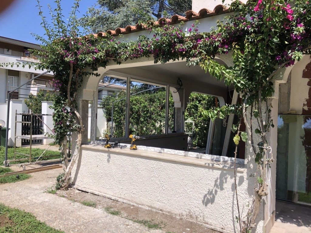 Veranda in alluminio sotto un pergolato fiorito
