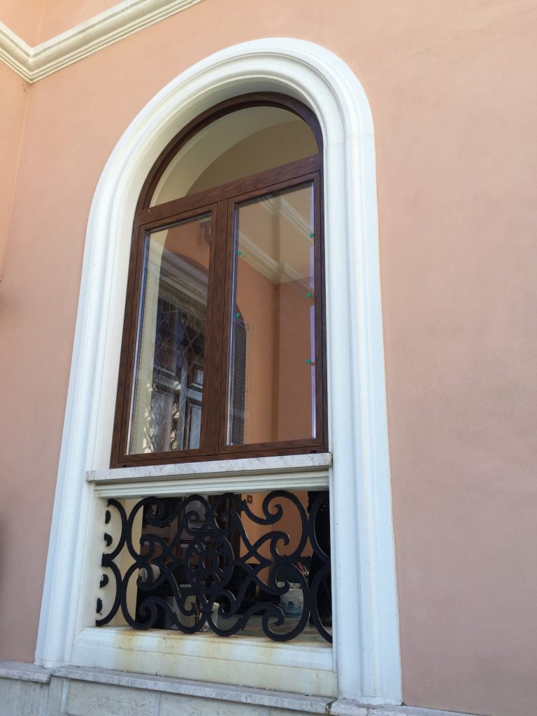 Finestra ad arco effetto legno con inferriata decorata