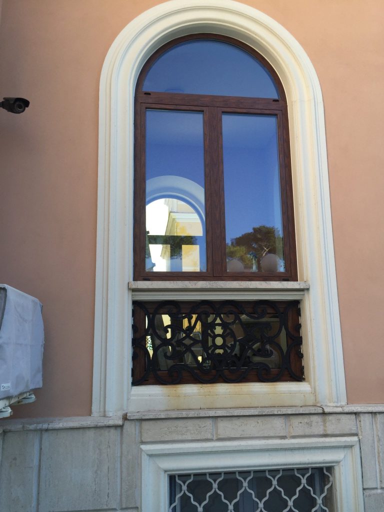 Finestra ad arco con inferriata decorata e grata in basso