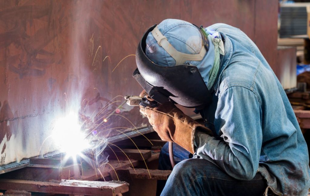 Saldatore al lavoro con maschera e scintille