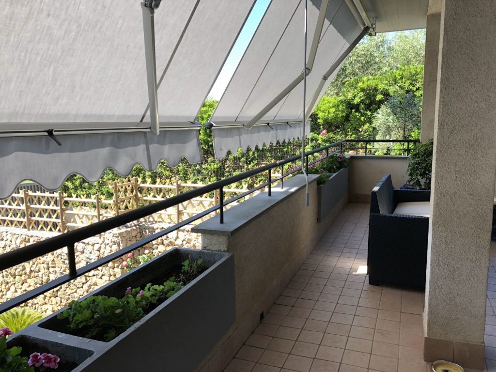 Ringhiera su fioriere di un terrazzo coperto da tenda