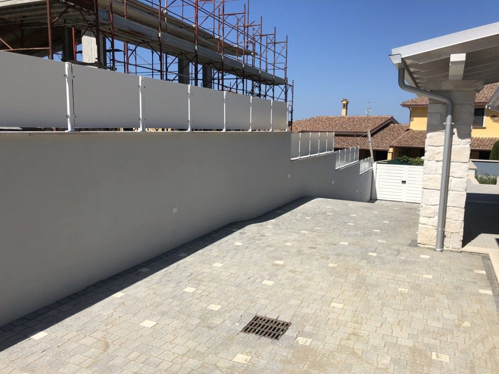 Parapetto a pannelli bianchi su muro di contenimento