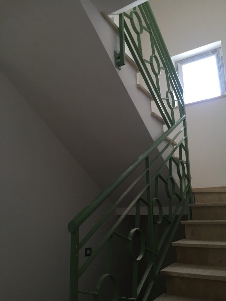 Ringhiera verde su scala condominiale, vista dal basso