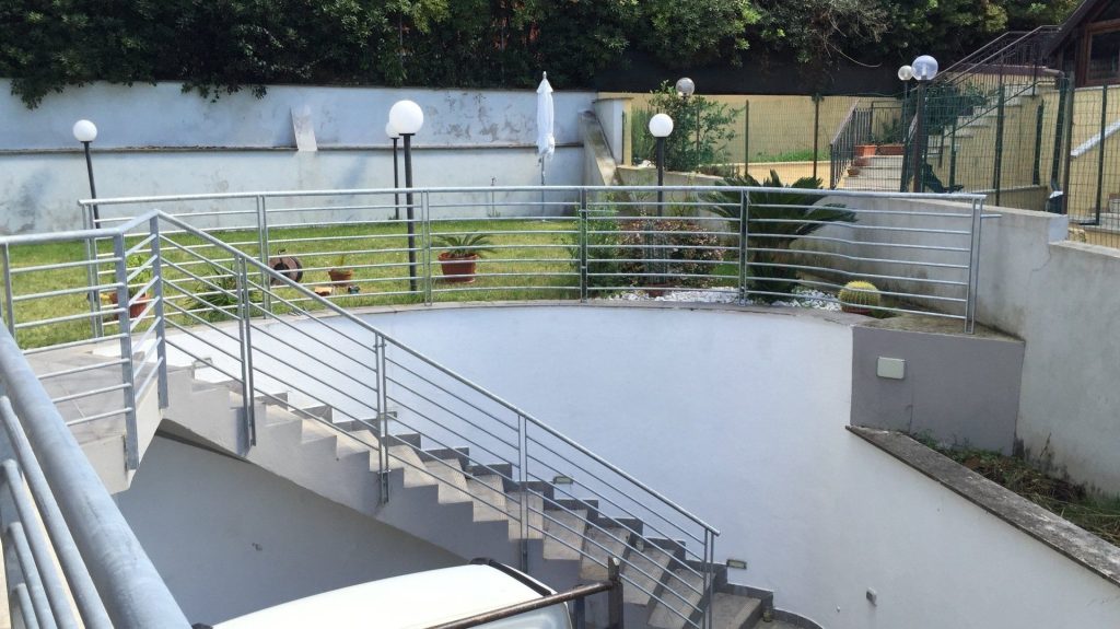 Ringhiera in acciaio lungo una scala esterna verso il giardino