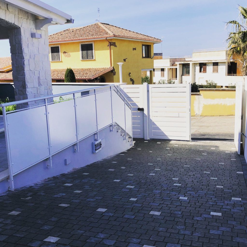 Rampa con parapetto a pannelli bianchi e cancello
